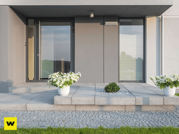 Moderner Hauseingang mit großen Glasflächen, Pflanzkübeln und minimalistischer Gestaltung.